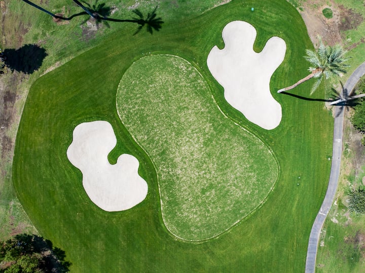 Eagle-eye view of the green on Hole 1 at The Springs Country Club, highlighting the putting surface and surrounding landscape.