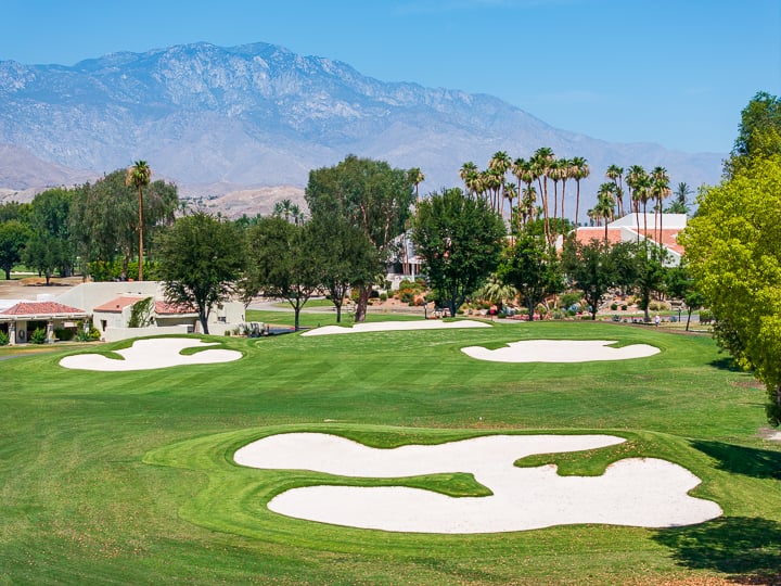 View of the bunker on Hole 18 at The Springs Country Club, positioned near the green and framed by surrounding fairway and landscape.
