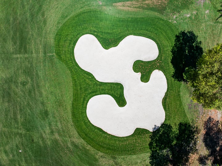 View of the bunker on Hole 18 at The Springs Country Club, positioned near the green and framed by surrounding fairway and landscape.