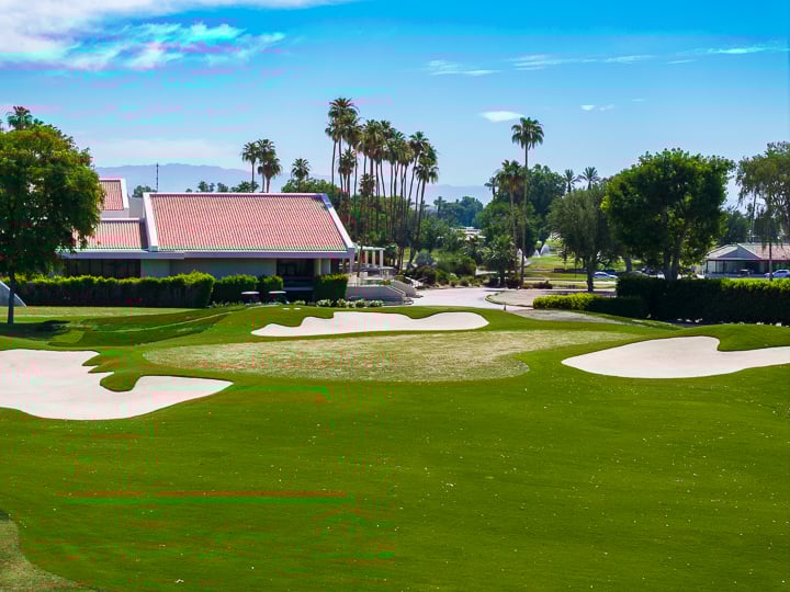 Distant view of the green on Hole 3 at The Springs Country Club, framed by fairway contours and surrounding desert landscape.