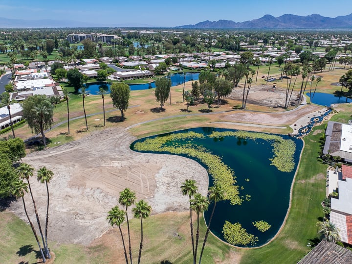 Active demolition on Hole 8, with turf removed and construction equipment reshaping the green and surrounding features.