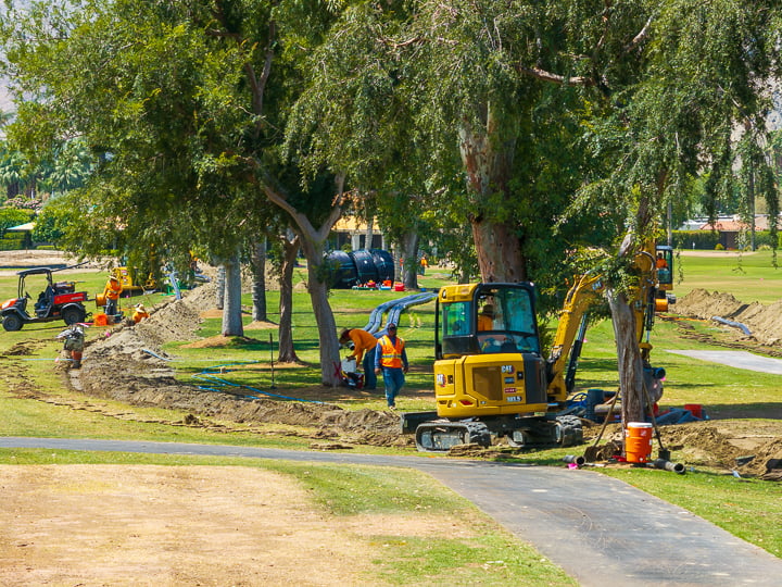 Ground-level view of main irrigation line installation between Holes 10 and 18 at The Springs Country Club, showing trenching and infrastructure work in progress.